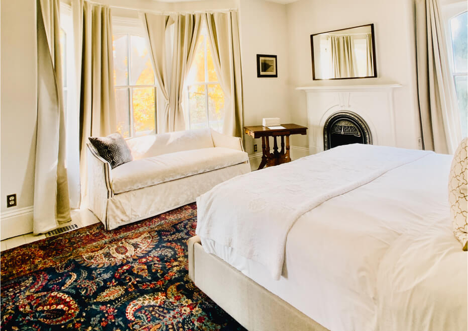 Elegant bedroom with a white bed, cream sofa, and fireplace