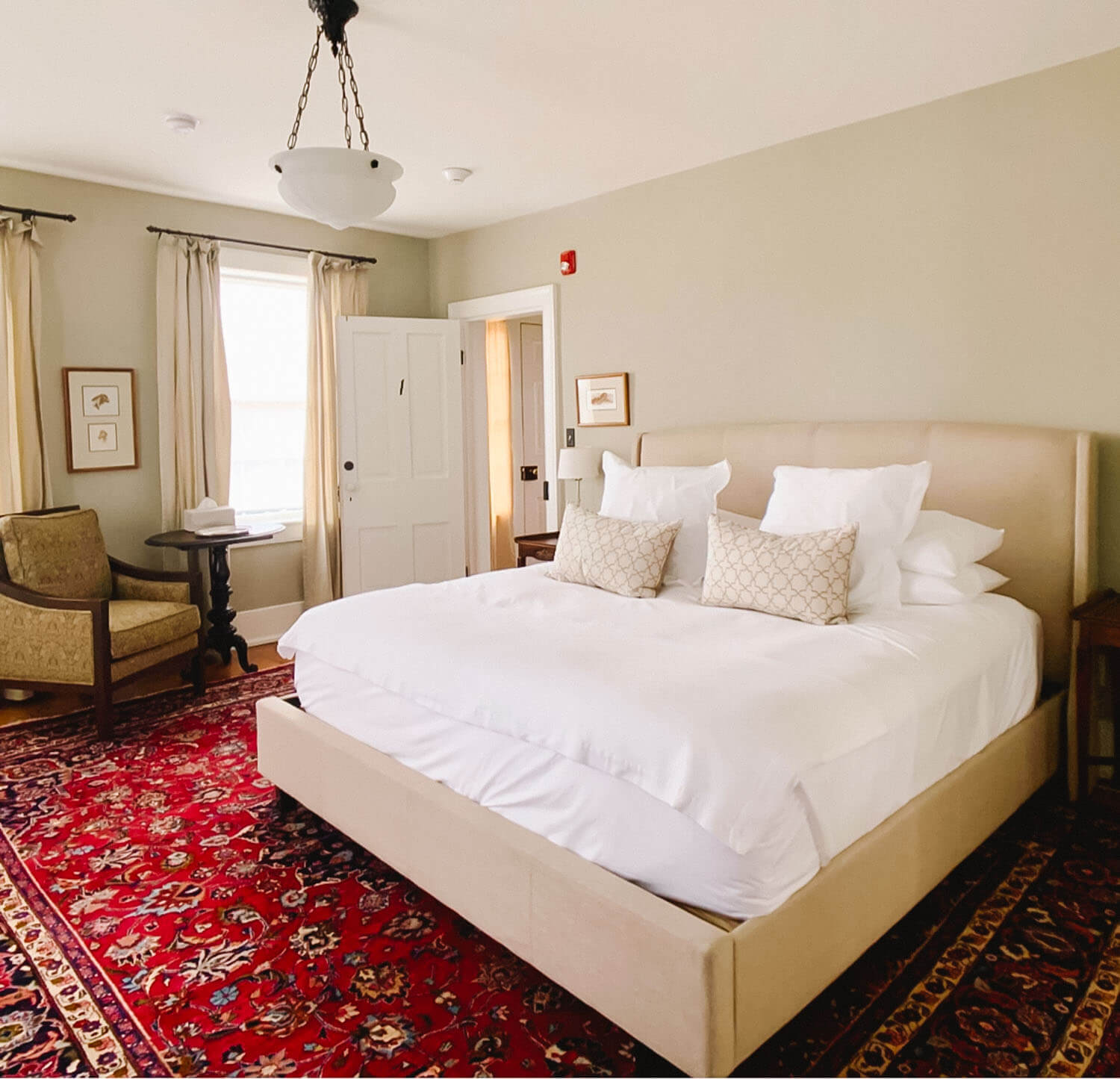 Bedroom with a tufted upholstered king bed and a red Persian-style rug